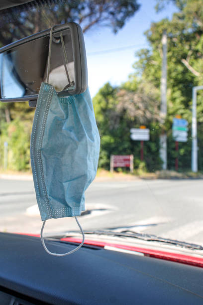 istock Face mask in the rearview mirror of a car while driving. 1256676766