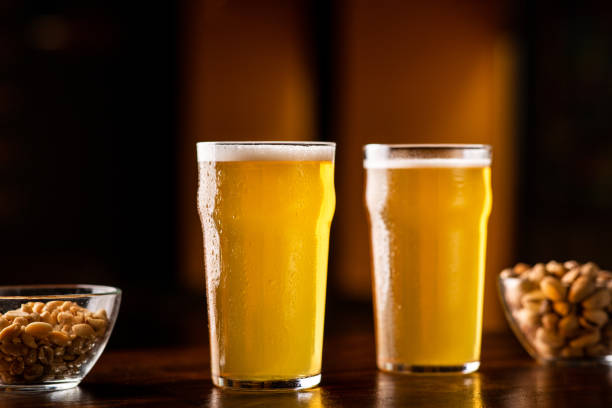 istock Beer set in pub. Two glasses of ale, nuts and pistachios on table in interior 1256677102