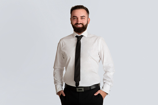 Smiling corporate employee in white shirt and tie on grey background