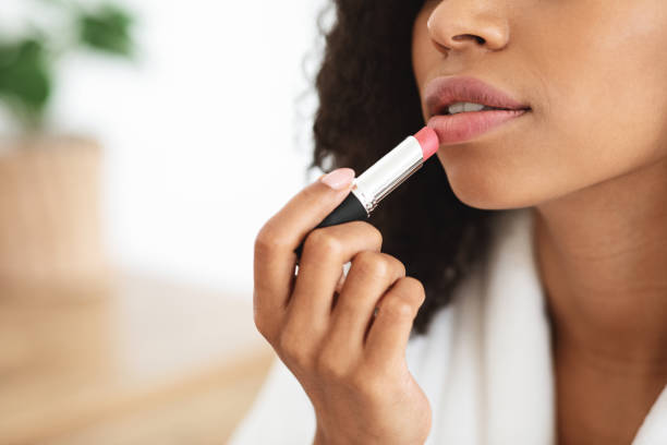 primer plano de la mujer afroamericana aplicando el lápiz labial de color desnudo, haciendo maquillaje diario - make up fashion beauty sullen fotografías e imágenes de stock