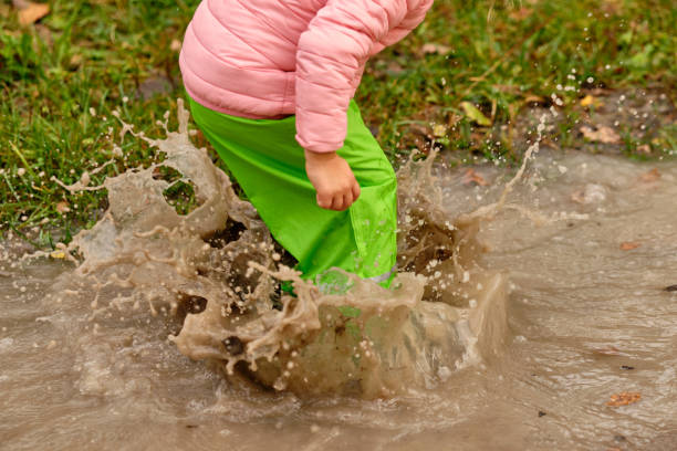istock Low section of a child jumping into rain puddle 1256680299
