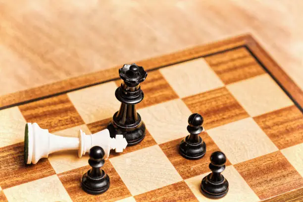 Fallen king symbolizes white's resignation in a chess game.