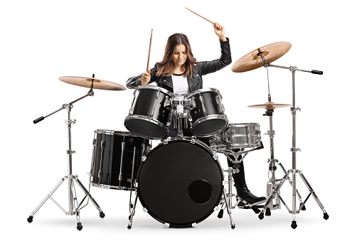Young female drummer playing drums with drumsticks isolated on white background