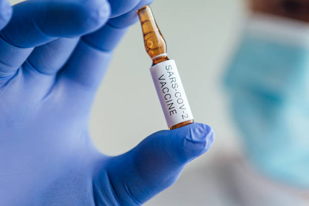 istock Doctor's hand with blue glove holding container with COVID-19 vaccine 1256684169