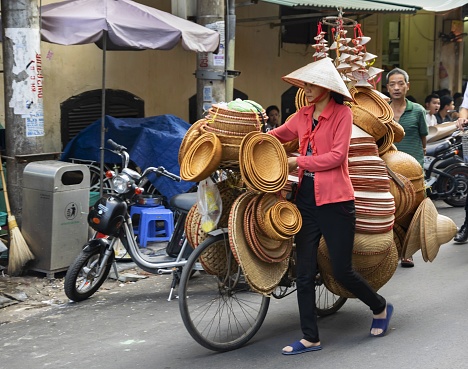 Hanoi, Vietnam, November 24, 2014: A woman carries some goods to sell it on the street market. The streets in the downtown of the Vietnamese capital serve as a market place.