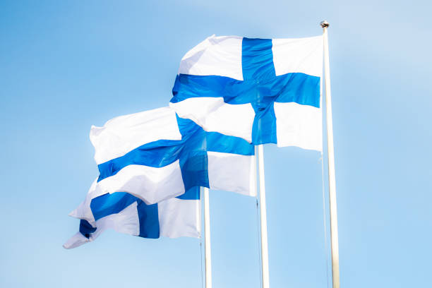 istock Three finnish national flags on the wind against the blue sky 1256687998