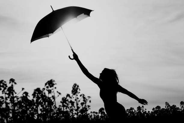 unplugged silueta libre mujer paraguas hasta el cielo blanco negro - white mid air rain wind fotografías e imágenes de stock