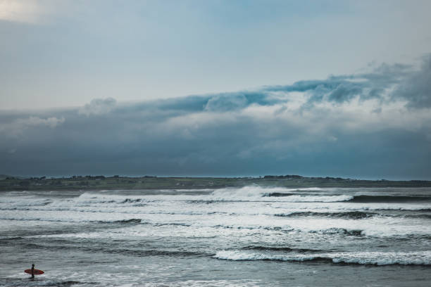 Surfer approaches the ocean waves. Surfing a wave around Strandhill Beach is an adventure. It calls for courage, resolve and fearlessness. Keep fit and recreational concept - County Sligo, Ireland