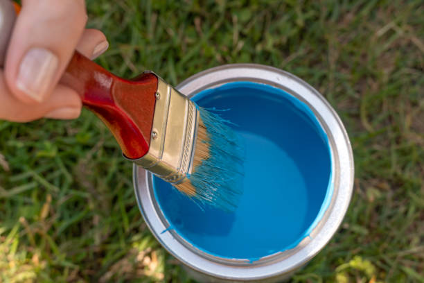 istock woman's hand dips a brush into a jar of blue paint close up 1256694461