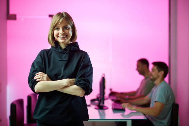 Young girl designer and his creative design team at the office during developing a new project, pink neon background