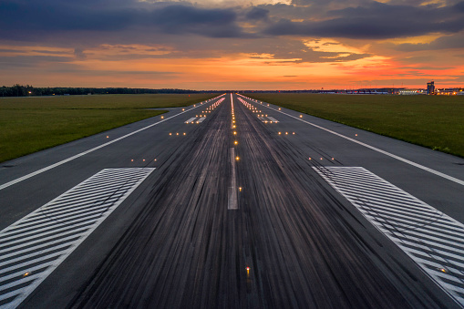 Used concrete asphalt airport empty runway with many braking marks, markings for landings and all navigation lights on