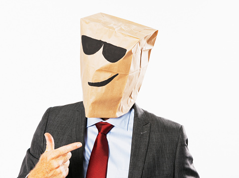 Suited businessman in shades gestures cheerfully.