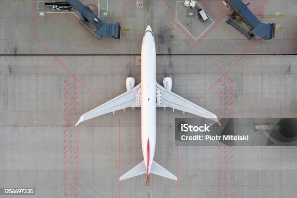 Top Down View On Comercial Airplane Docking In Terminal In The Parking Lot Of The Airport Apron Waiting For Services Maintenance Refilling Fuel Services After Airspace Lock Down Modern Airliner Stock Photo - Download Image Now