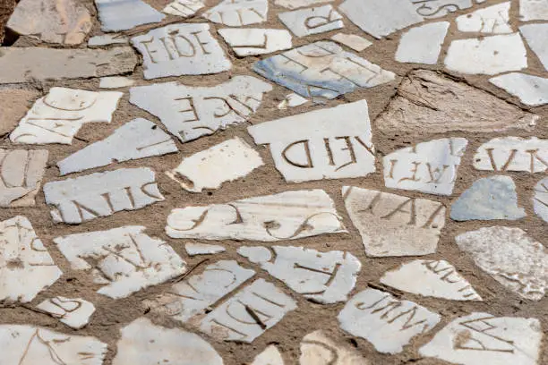 Old pavement made of marble pieces with latin letters illustrating difficullties of information decoding without order.
