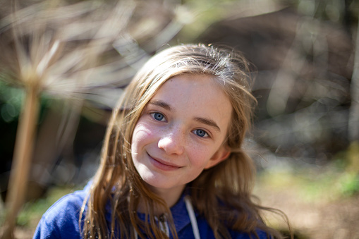 A close-up shot of a young, Caucasian girl walking through woodland in a forest in Northumberland, Northeastern England.