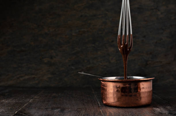 istock Liquid chocolate cream pouring from a whisk into a ladle. 1256699734