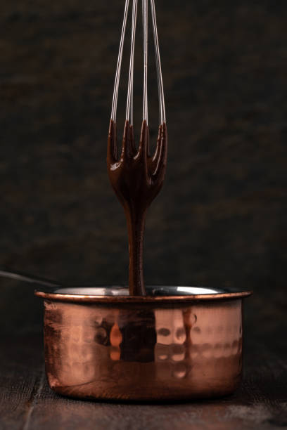 istock Liquid chocolate cream pouring from a whisk into a ladle. 1256699737