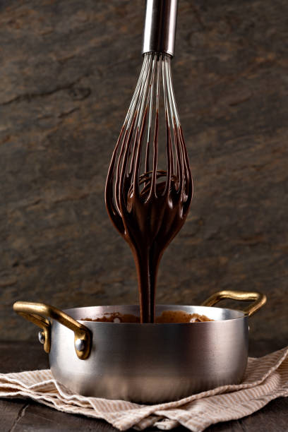 istock Liquid chocolate cream pouring from a whisk into a ladle. 1256699745