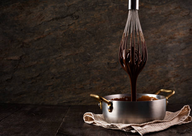 istock Liquid chocolate cream pouring from a whisk into a ladle. 1256699752