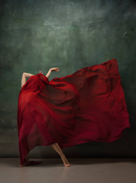 istock Young graceful tender ballerina on dark green studio background 1256699833