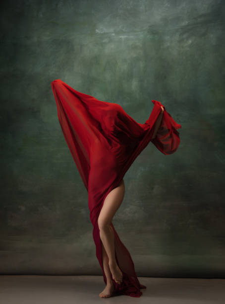 istock Young graceful tender ballerina on dark green studio background 1256699838