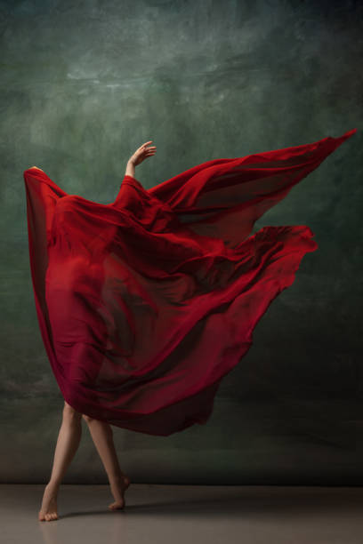istock Young graceful tender ballerina on dark green studio background 1256699841