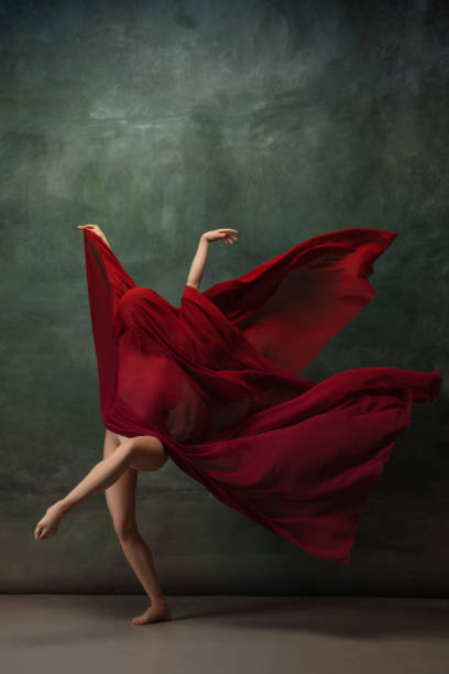istock Young graceful tender ballerina on dark green studio background 1256699846