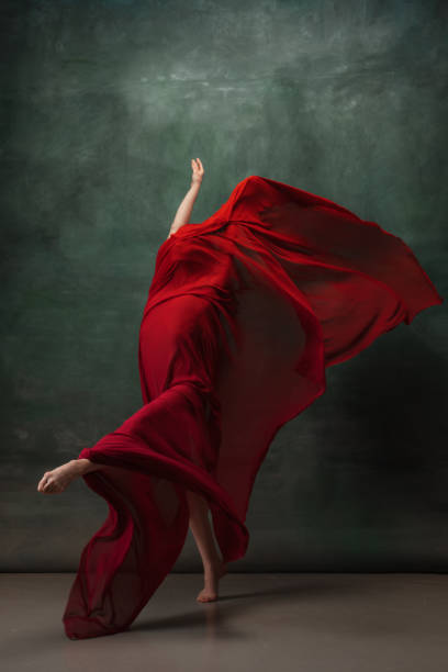 istock Young graceful tender ballerina on dark green studio background 1256699857