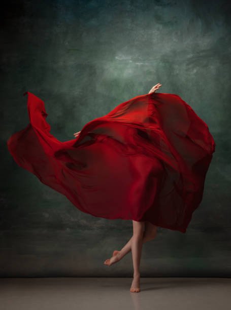 istock Young graceful tender ballerina on dark green studio background 1256699863