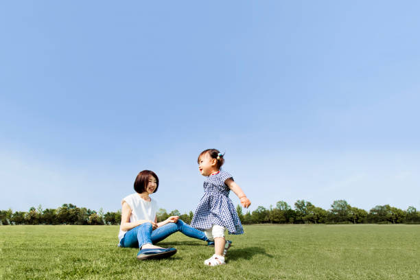 istock Mather and little daughter playing on green grass square against blue sky 1256701070