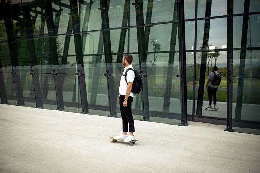 Young modern businessman commuting on skateboard