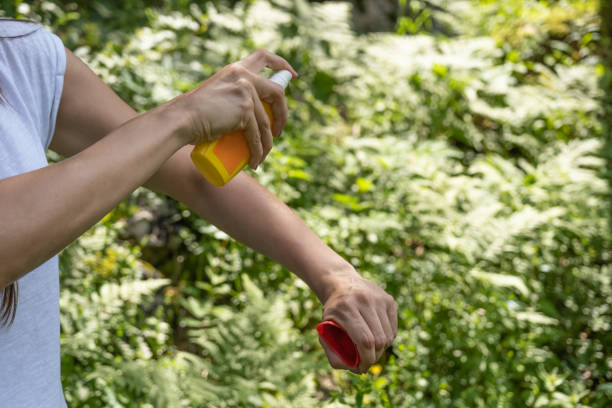 istock Woman applying mosquito repellent on arm 1256702916