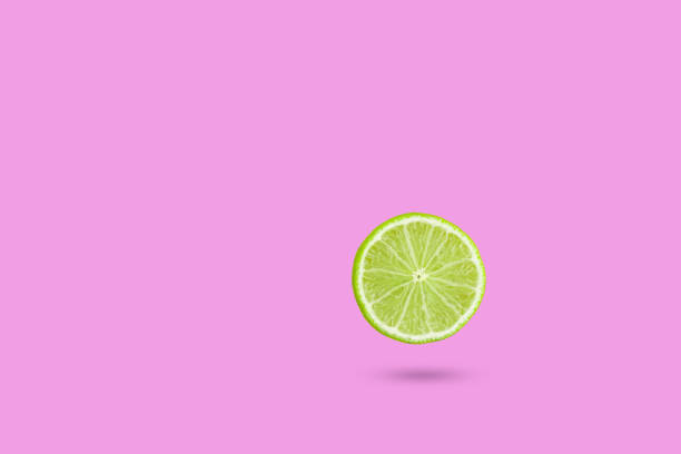istock Green lime slic on vibrant pink color background. Minimal summer concept. 1256704033