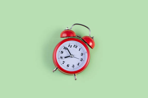 istock Red vintage alarm clock on light green color background. 1256704045
