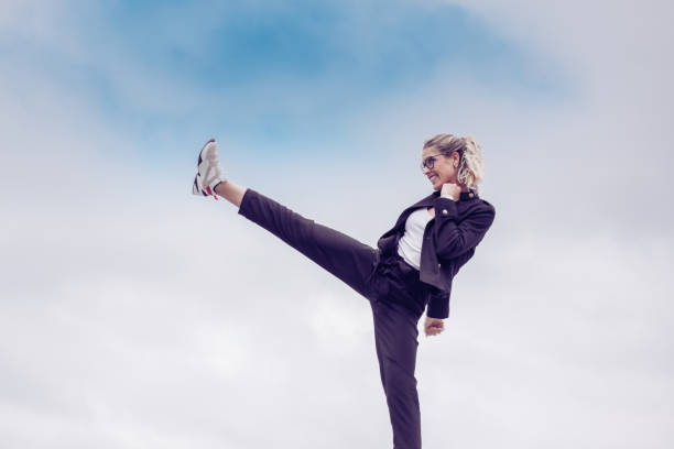 Young woman kicking as a sign of strength and addiction . In the background the blue sky. Kick it like a lady Concept. Young woman kicking as a sign of strength and addiction . In the background the blue sky. Kick it like a lady Concept. career vitality stock pictures, royalty-free photos & images
