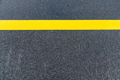 Asphalt road with single yellow line.