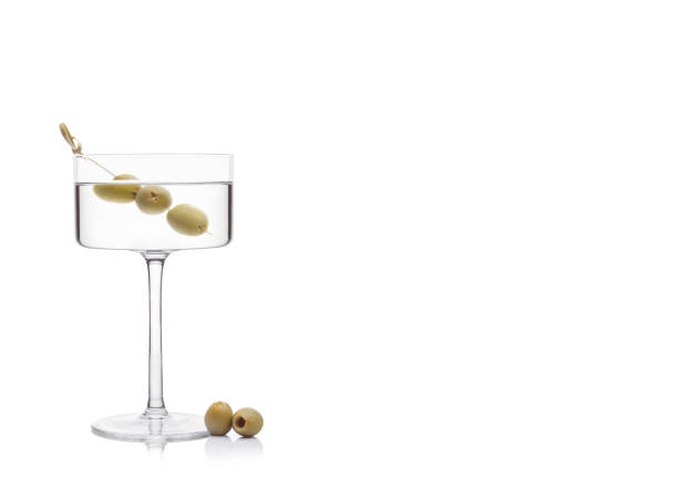 wódka martini gin koktajl w nowoczesnym szkle z oliwkami na bambusa kij ze świeżymi zielonymi oliwkami na białym tle z refleksem. - gin tonic water martini olive zdjęcia i obrazy z banku zdjęć