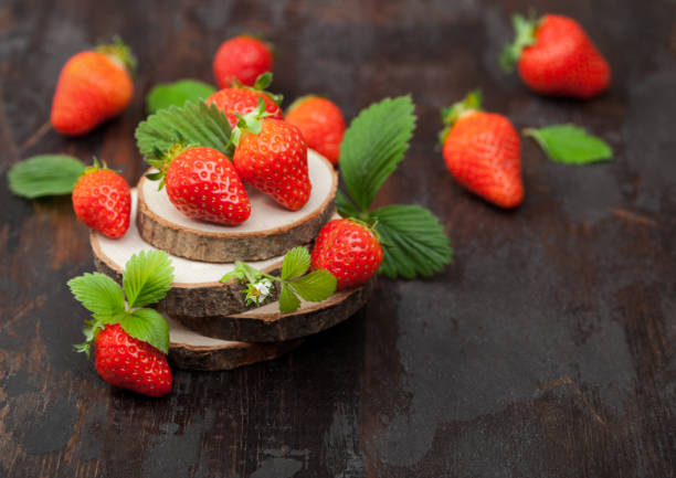 istock Organic fresh raw strawberries with leaf on timber round boards on dark background. 1256709706