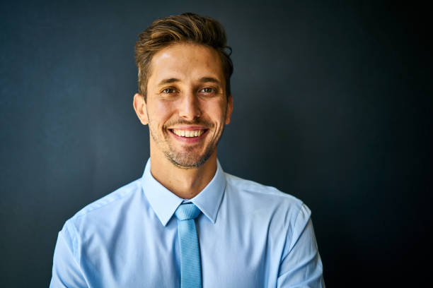 istock Confident young businessman smiling against a black background 1256710913