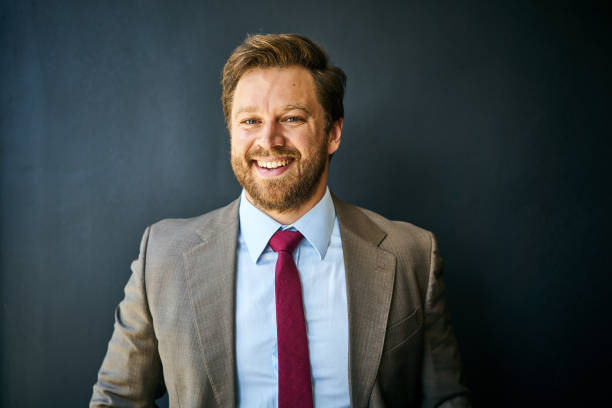 istock Businessman laughing while standing in front of a black background 1256711271