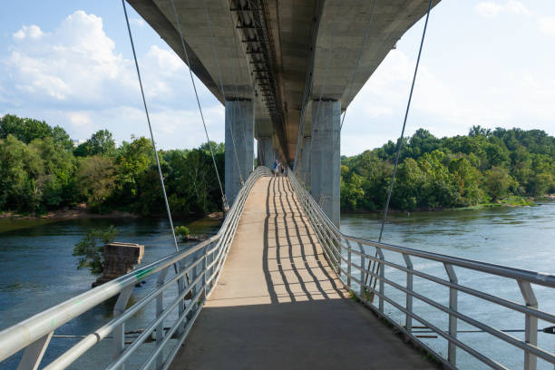 Belle Isle Suspension Bridge over the James River in Richmond, Virginia RICHMOND, VIRGINIA - August 9, 2019: People walk over the Belle Isle suspension bridge on a beautiful summer day belle isle stock pictures, royalty-free photos & images