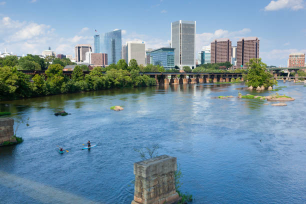 Richmond Virginia Skyline from the James River RICHMOND, VIRGINIA - August 9, 2019: The Richmond skyline is seen over the James River on a late summer day. Paddleboarders and kayakers enjoy the river. belle isle stock pictures, royalty-free photos & images