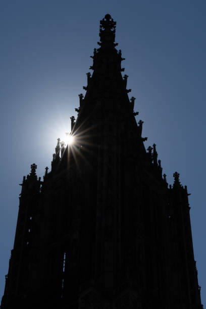 silhouette of the cathedral spire of the minster in Ulm with a sun star The silhouette of the cathedral spire of the minster in Ulm with a sun star ulm germany stock pictures, royalty-free photos & images