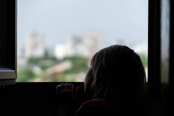 Dark silhouette of a child in the background of an apartment building
