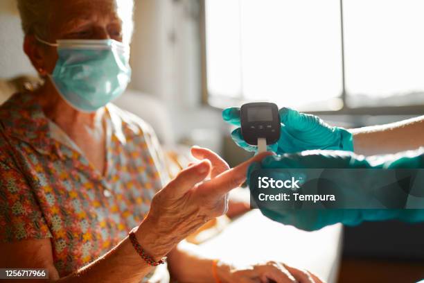 A Nurse Helping A Senior Woman Perform A Diabetes Test Stock Photo - Download Image Now