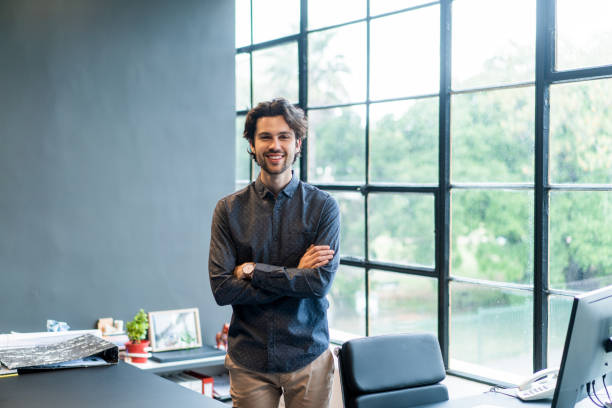 istock Young designer smiling while standing by his office desk 1256718663