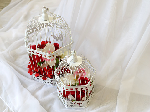 Wedding decorations: white cell with flowers on a fabric background. Celebration