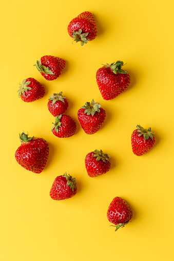 Fresh strawberry at yellow minimal background. Minimal concept of ripe vegan food. Top view, flat lay, place for text, sale at market