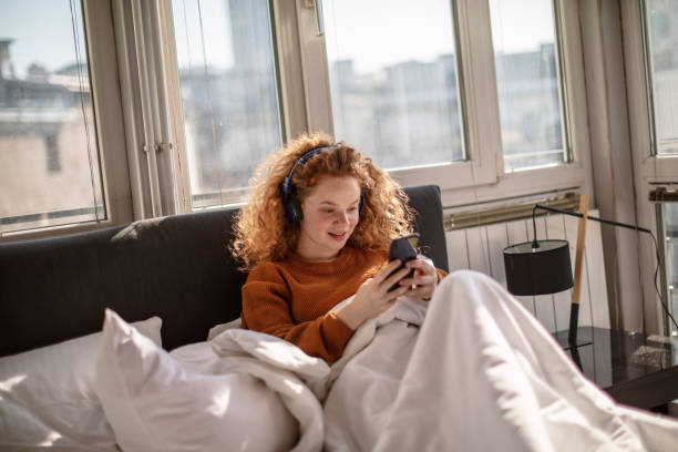 istock Young woman using a mobile phone in bed 1256719520