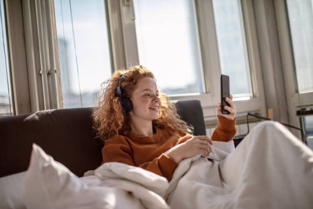 istock Young woman using a mobile phone in bed 1256719742